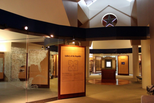 Interior view of a museum gallery featuring displays and a large star-shaped window above.