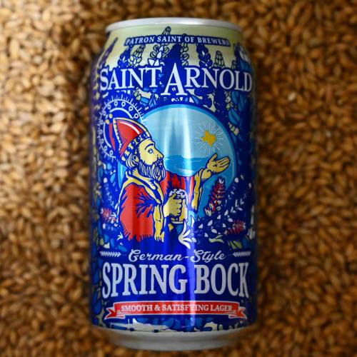A colorful can of Saint Arnold Spring Bock beer featuring a saintly figure and floral designs on a textured background.