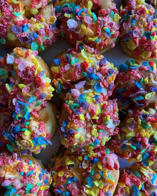 A close-up of colorful donuts topped with icing and vibrant cereal sprinkles.