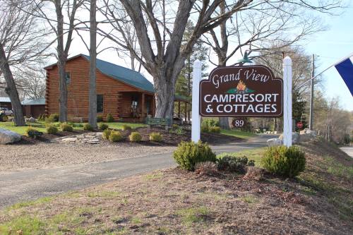 Sign for Grand View Camp Resort & Cottages, with a log cabin and landscaped grounds in the background.