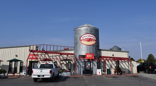 Exterior of Great Montana Bakery & Deli, featuring a silvery grain silo and red accents, with a truck parked outside.