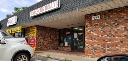 Exterior of Carlson's Donuts shop, featuring a brick facade and an open sign in the window.