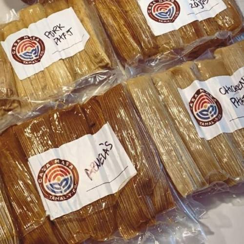 Packages of tamales labeled with flavors like pork and chicken, neatly arranged and wrapped in clear plastic.