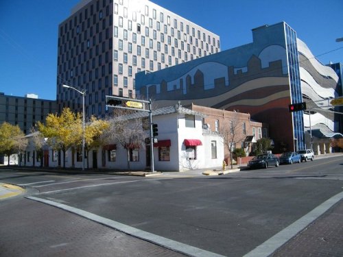 A street view featuring a historic building with red awnings and a modern, colorful building in the background.