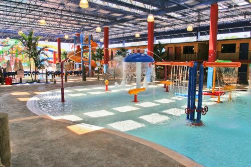 Indoor water park featuring colorful play structures, splash pads, and seating areas under a bright ceiling.