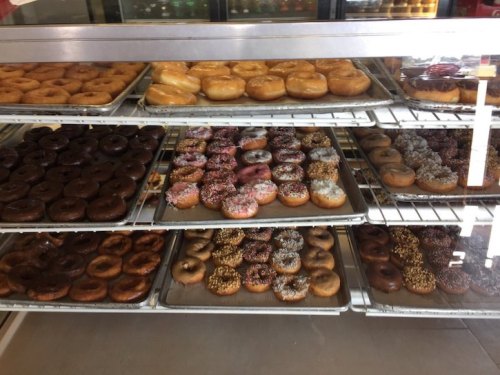 A display case filled with various donuts, including glazed, chocolate, and sprinkled varieties.