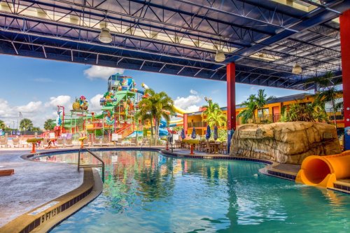 A vibrant water park with a large slide, pool area, and colorful play structures under a blue sky.
