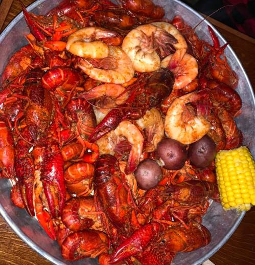 A large metal bowl filled with crawfish, shrimp, potatoes, and corn, showcasing a colorful seafood feast.