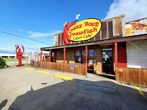 Exterior of Crazy 'Bout Crawfish Cajun Café, featuring a bright sign and a large red lobster sculpture outside.