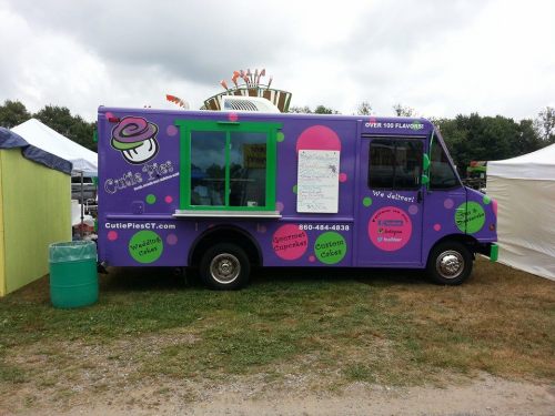 A colorful food truck named "Cutie's Cakes" with a cupcake logo, offering various desserts and delivery services.