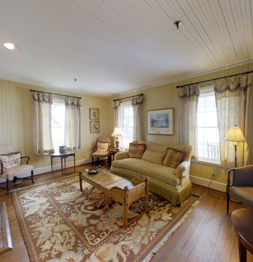 Cozy living room with a sofa, armchairs, a wooden coffee table, and large windows letting in natural light.