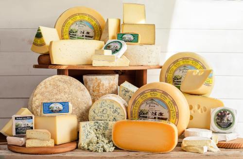 A variety of cheeses displayed on wooden boards, featuring different shapes, sizes, and labels.