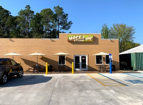 Exterior of Hope's restaurant with outdoor seating, umbrellas, and a clear blue sky in the background.