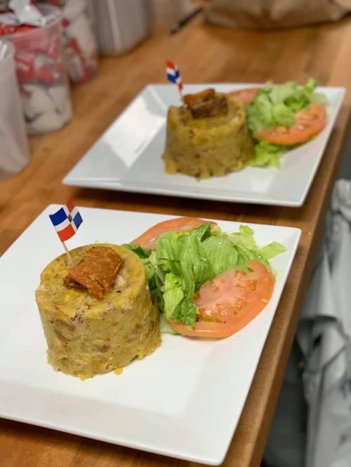 Two plates of Dominican mofongo topped with meat, served with lettuce and tomato, garnished with small flags.