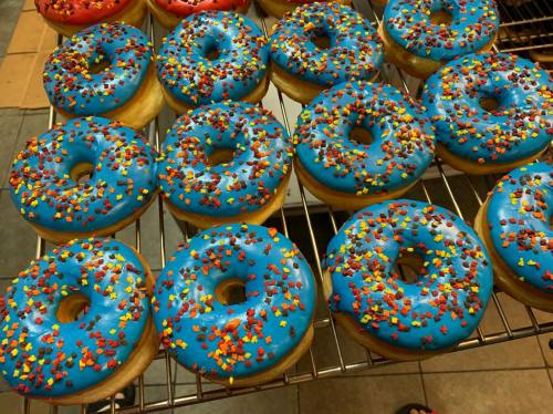 A tray of blue frosted donuts topped with colorful sprinkles, arranged in a grid pattern.