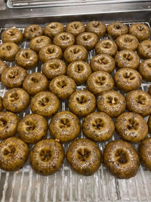 A tray filled with freshly made, golden-brown donuts arranged in neat rows.