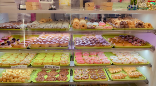 A display case filled with various colorful donuts, including glazed, frosted, and sprinkled varieties.