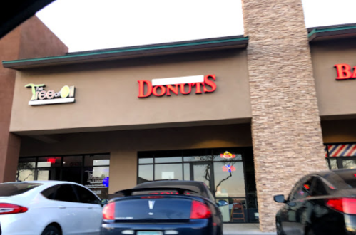 A storefront featuring a sign for "Donuts" and a nearby sign for "The Tree." Two parked cars in front.