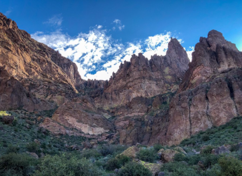 A dramatic landscape featuring rugged rock formations under a blue sky with scattered clouds.