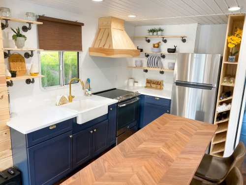 Modern kitchen with navy cabinets, a farmhouse sink, wooden accents, and stainless steel appliances. Bright and inviting space.