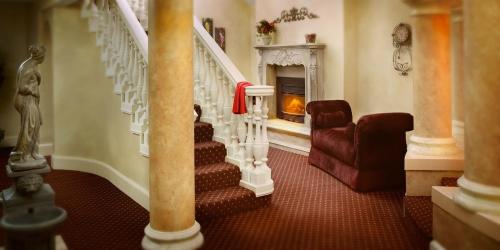 Elegant interior featuring a staircase, plush armchair, decorative columns, and a cozy fireplace.