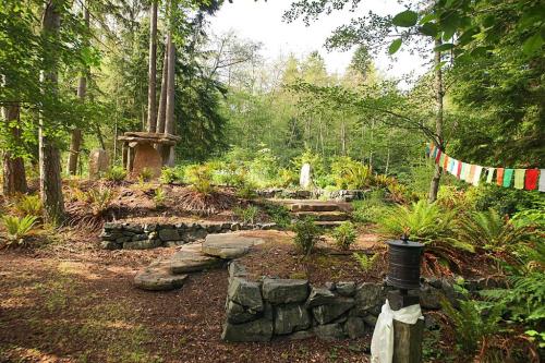 A serene forest garden with stone paths, lush greenery, and colorful prayer flags hanging among the trees.