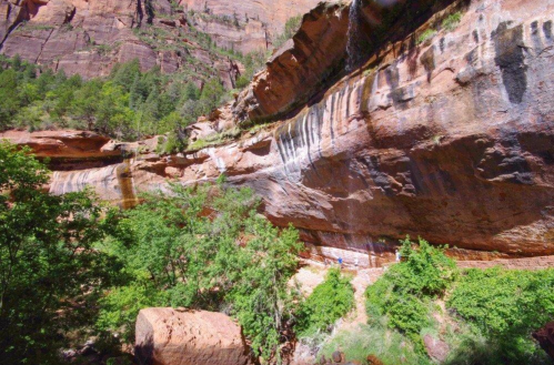 A scenic view of a rocky canyon with waterfalls and lush greenery in a natural landscape.