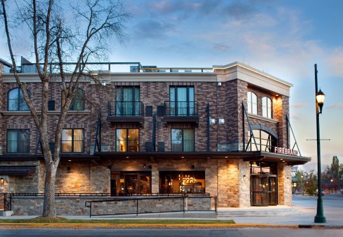 A modern brick building with a restaurant named "Firebrand" and outdoor seating, set against a twilight sky.