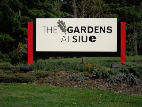 Sign for "The Gardens at SIUE" surrounded by greenery and landscaping.