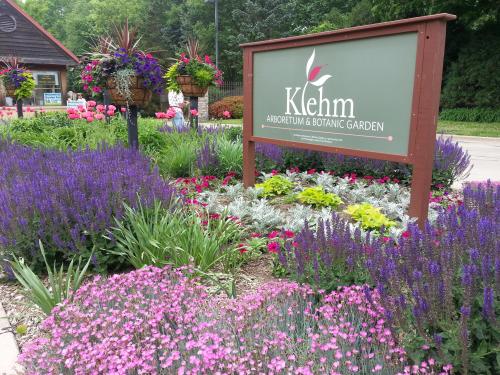 Sign for Klehm Arboretum & Botanic Garden surrounded by colorful flowers and lush greenery.