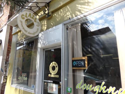 Exterior of Glaze Gourmet Doughnuts shop, featuring a sign that says "OPEN" and a bright, inviting atmosphere.
