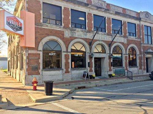 Historic brick building with large windows, featuring a sign for "The Vault" and showcasing art and gifts.