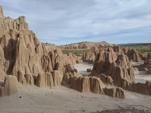 A rugged landscape of towering, sandy rock formations under a cloudy sky.