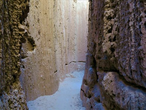 Narrow canyon walls of textured earth and rock, illuminated by soft light from above.