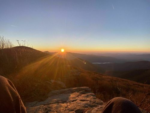 A breathtaking sunset over rolling mountains, with rays of sunlight illuminating the landscape.