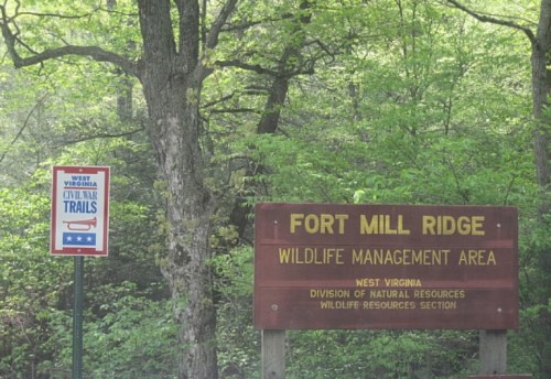Sign for Fort Mill Ridge Wildlife Management Area in West Virginia, surrounded by lush green trees.