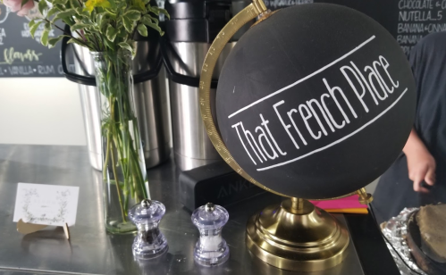 A chalkboard globe labeled "That French Place" next to a vase of flowers and salt and pepper shakers on a counter.