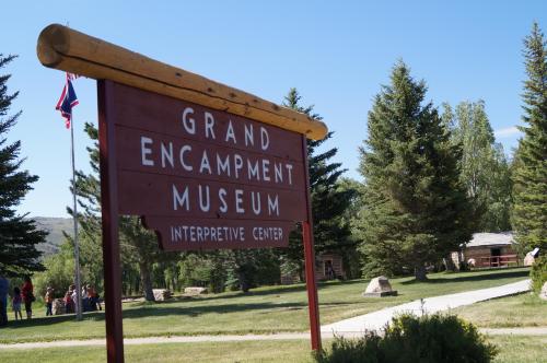 Sign for the Grand Encampment Museum Interpretive Center, surrounded by trees and a clear blue sky.