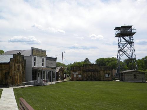 A historic western town with wooden buildings and a tall observation tower under a cloudy sky.