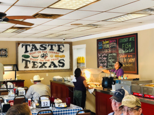A cozy diner with a "Taste of Texas" sign, featuring a buffet and patrons enjoying their meals at checkered tables.