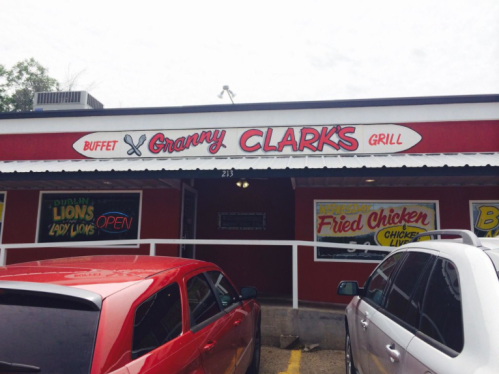 Sign for "Granny Clark's Grill" with a buffet and fried chicken, featuring red and white colors, and parked cars in front.