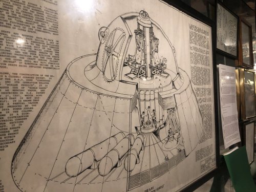 Blueprint of a futuristic spacecraft, featuring detailed interior and exterior designs, displayed on a wall.