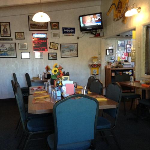 Cozy restaurant interior with tables set, colorful decor, a TV, and a flower centerpiece.