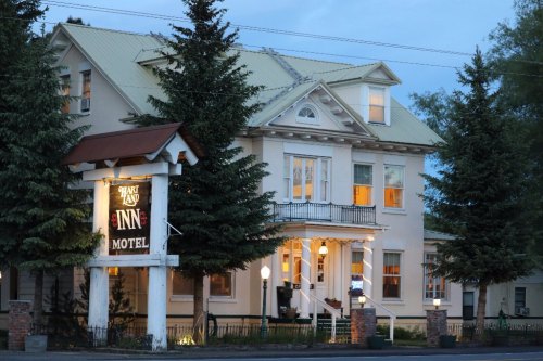 Historic inn with a porch, surrounded by trees, illuminated at dusk. Sign reads "Shady Land Inn & Motel."