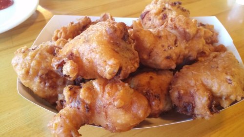 A tray of golden-brown, crispy fried chicken pieces piled together.