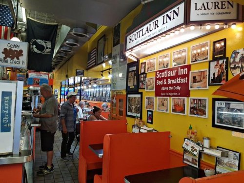 Interior of a diner with orange booths, a counter, and walls adorned with photos and signs for Scotlaur Inn.