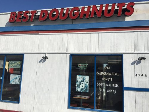 Sign for "Best Doughnuts" with a bright blue exterior, showcasing "Open" and advertisements for fresh California-style donuts.