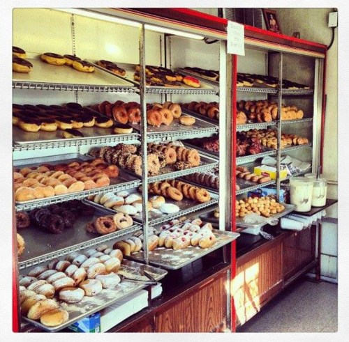 A display case filled with various types of donuts, including glazed, chocolate, and powdered sugar varieties.