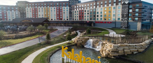 Aerial view of Kalahari Resort entrance with colorful buildings, a waterfall, and a large sign in front.