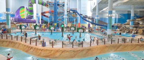 Indoor water park featuring slides, a large pool, and families enjoying the attractions. Bright and colorful environment.